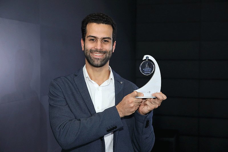 smiling awardee holding the award in his hand